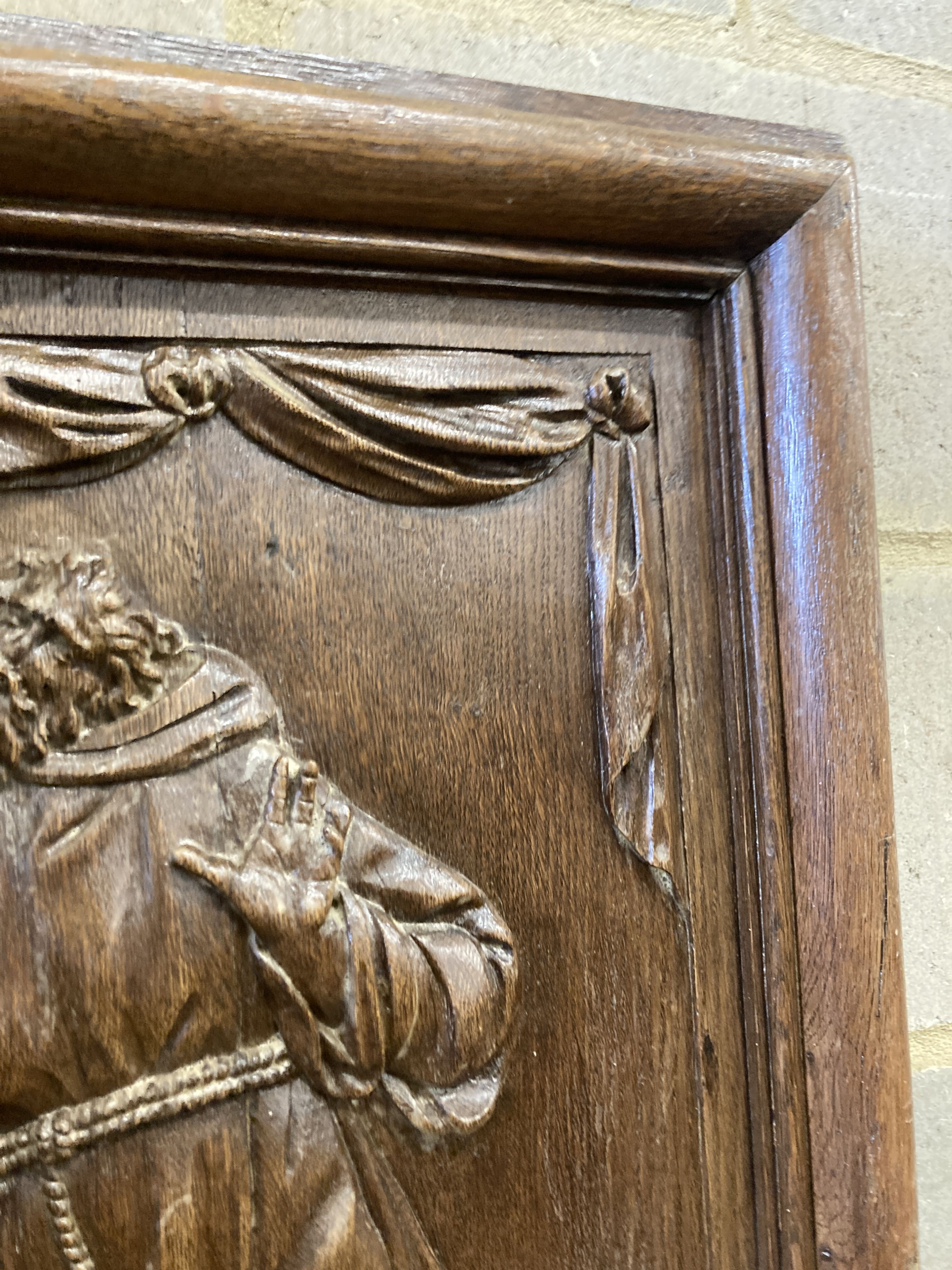 A rectangular carved oak wall panel depicting religious scene